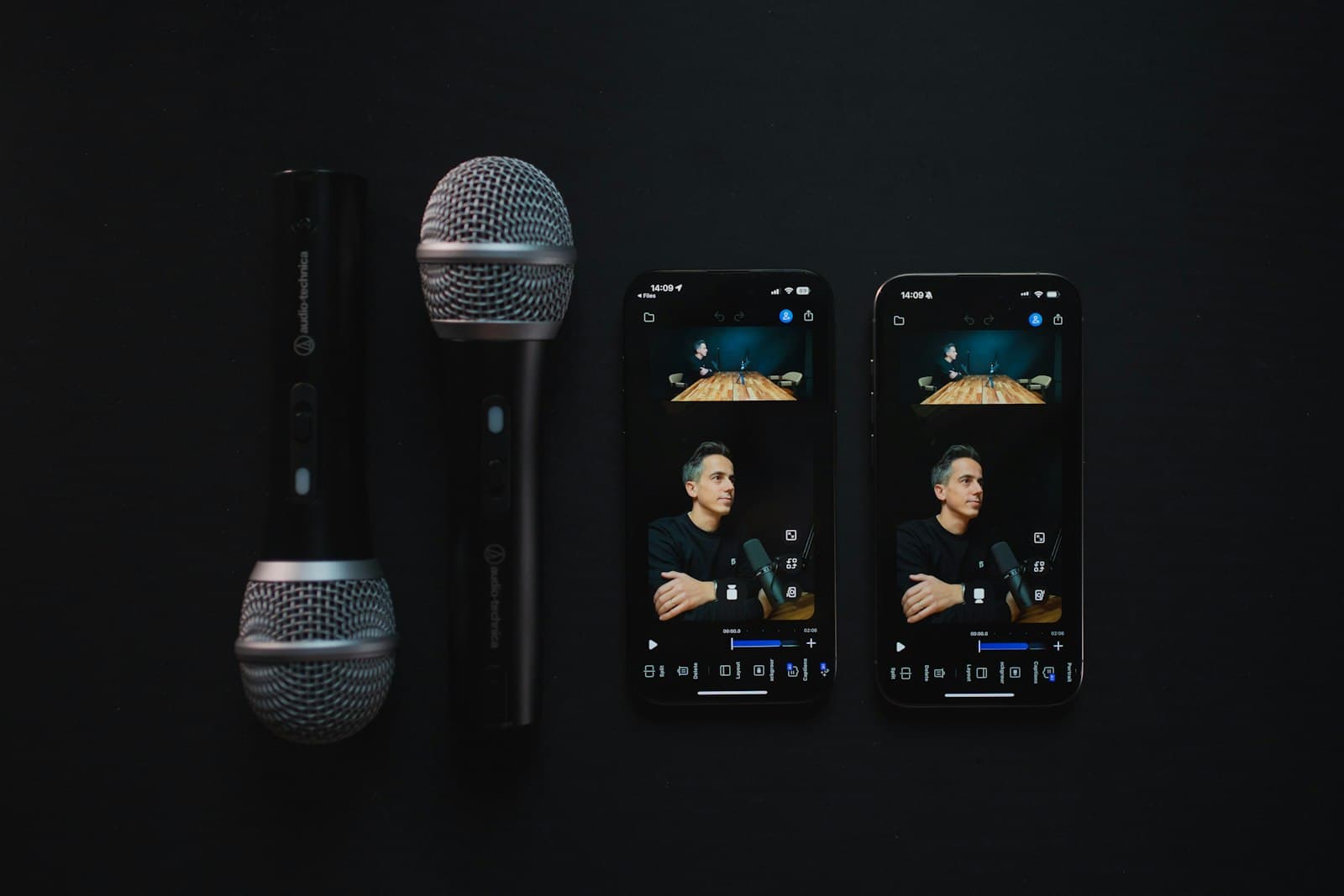 Two microphones beside phones showing a podcast episode being edited