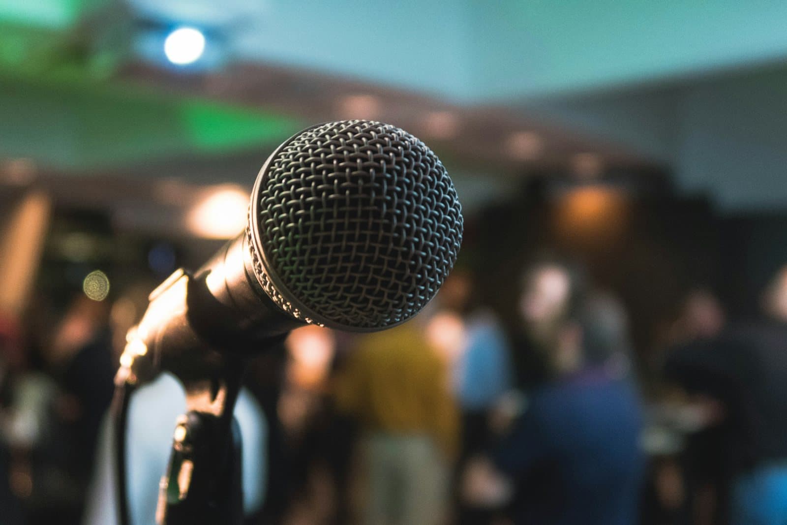 A microphone on stage in front of a warmly lit audience