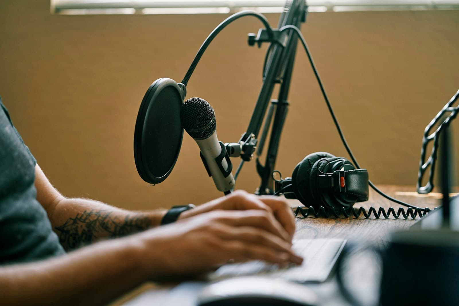A creator works at a home podcast setup with a boom-mounted microphone and pop filter
