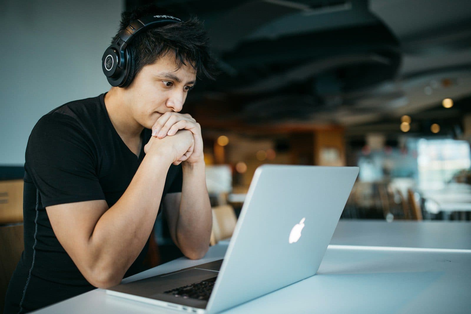 A podcast host in headphones working at a laptop in a home studio
