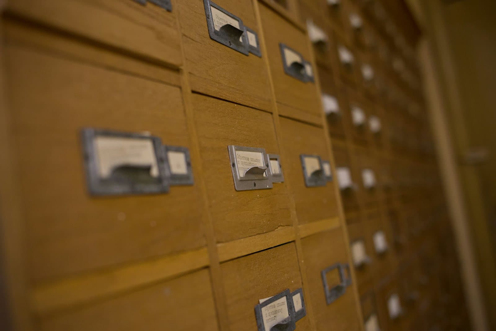 Rows of wooden card catalog drawers, each with a small metal label holder