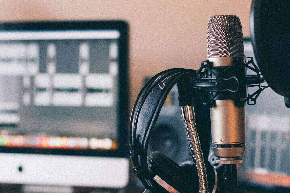 Studio headphones resting over a broadcast microphone in a dark recording room