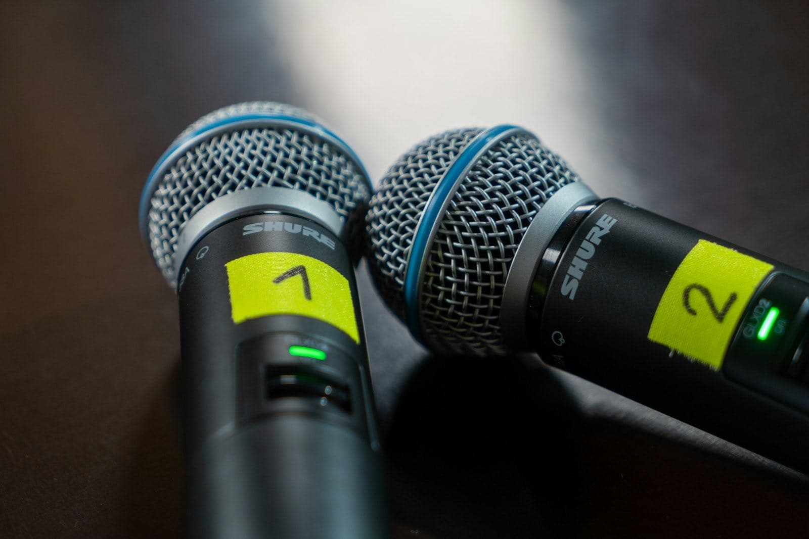 Two microphones set up side by side on a table for a panel discussion