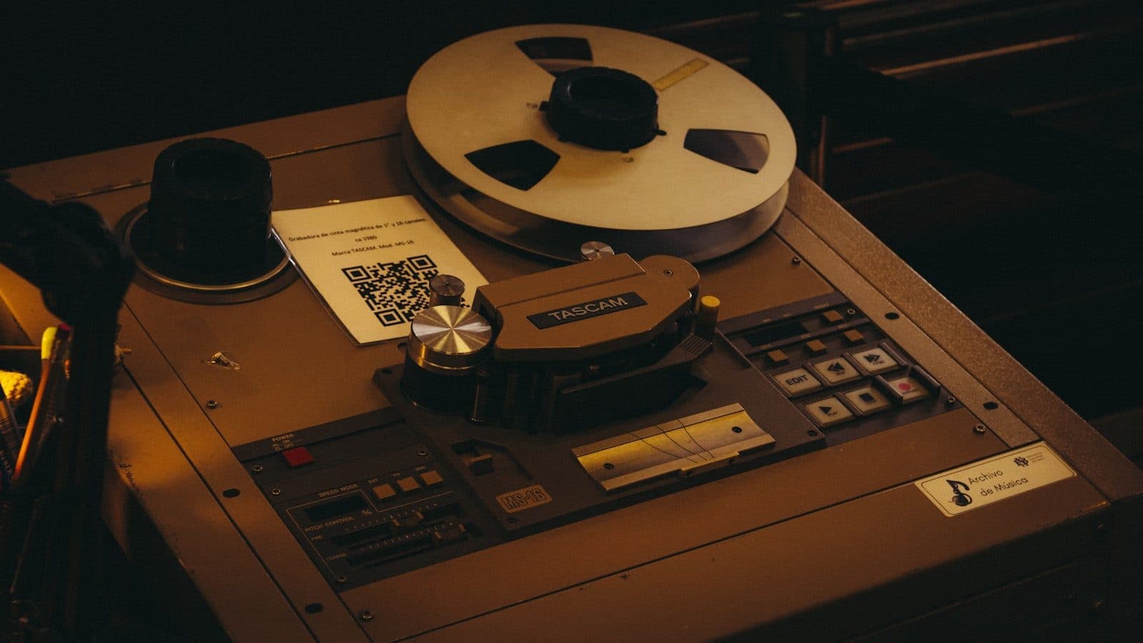 A vintage reel-to-reel tape recorder with a spool of tape on the deck