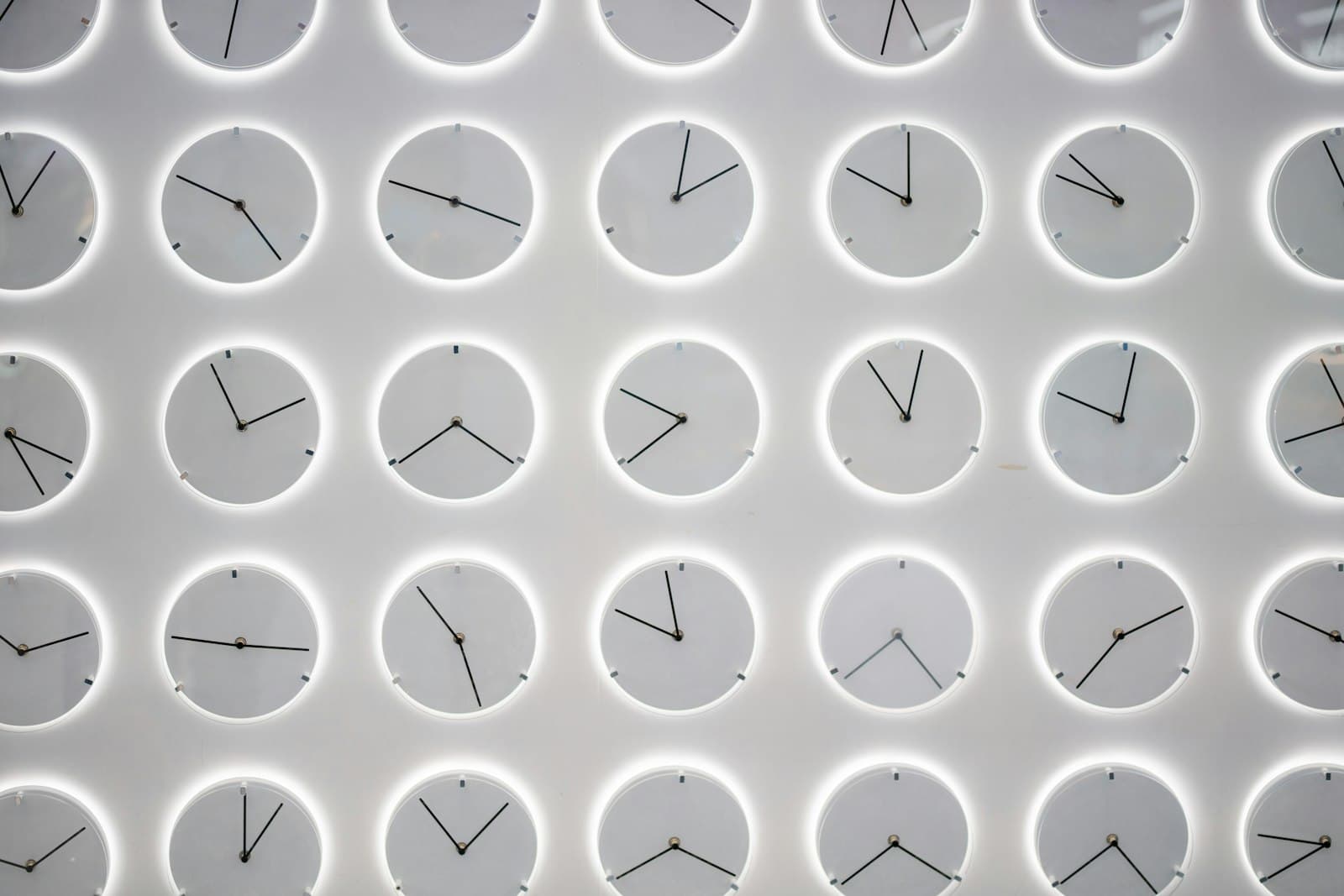 A wall covered in dozens of clocks, every one of them showing a different time