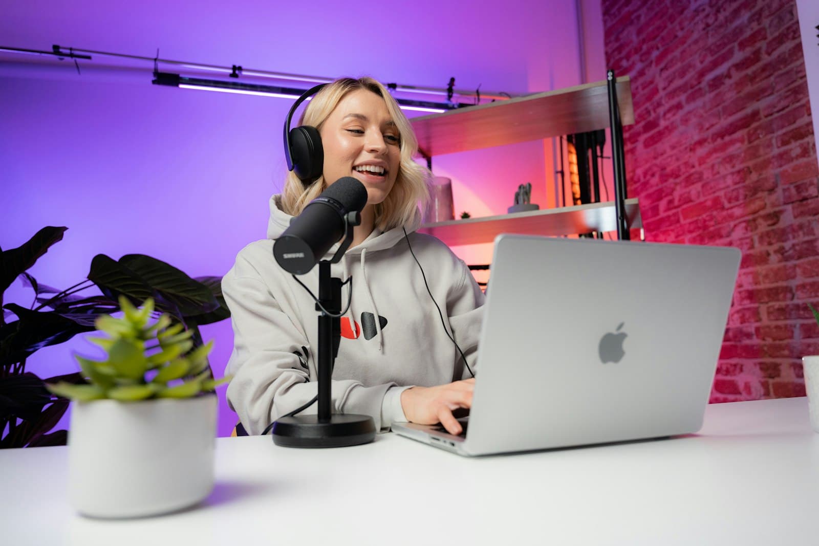 A podcast creator researches a show on a laptop beside a studio microphone