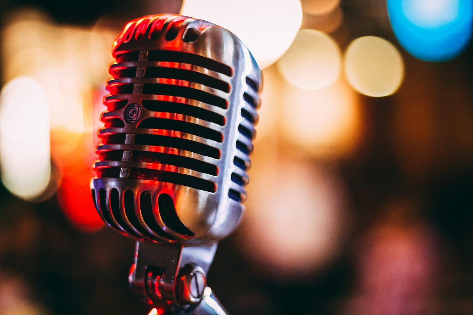A vintage broadcast microphone in front of warm out-of-focus lights