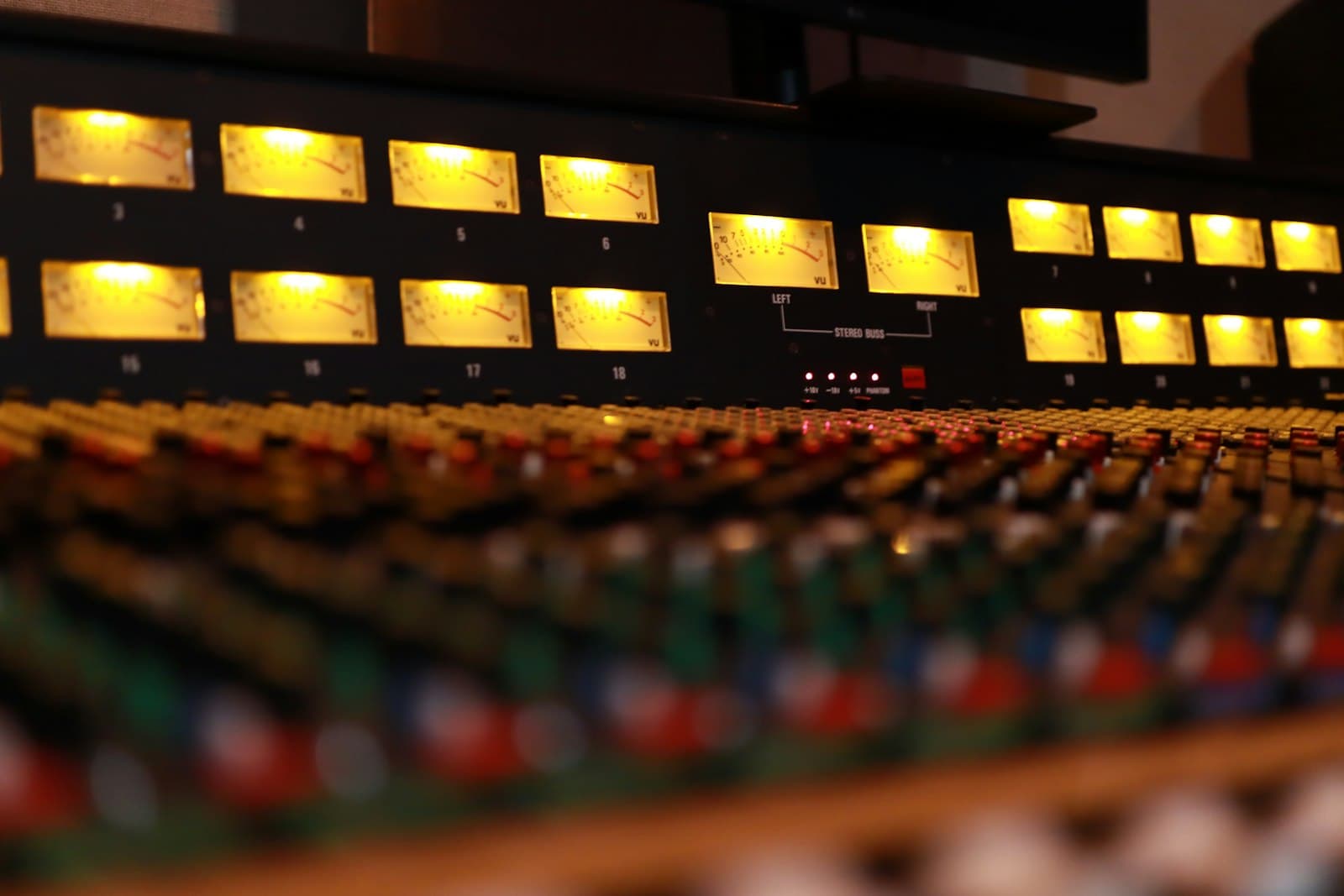 A close-up of a sound mixing console, its channel faders set at different levels