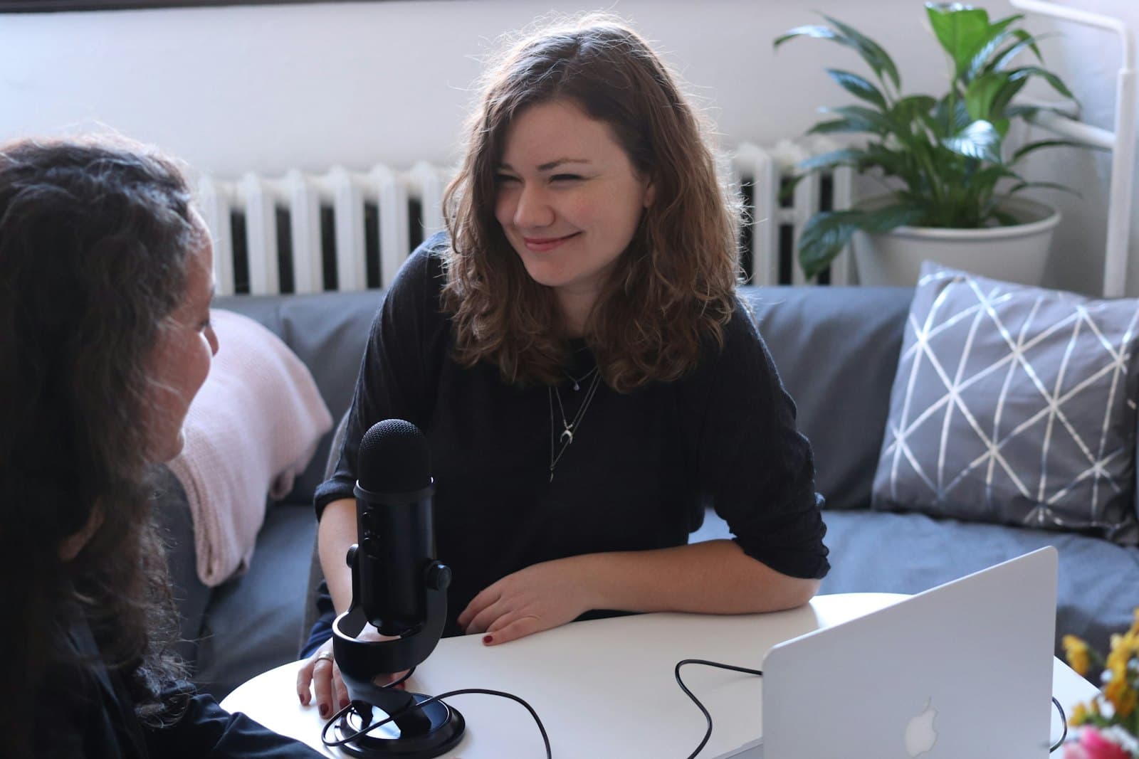 Two people in conversation across a table, one listening as the other speaks