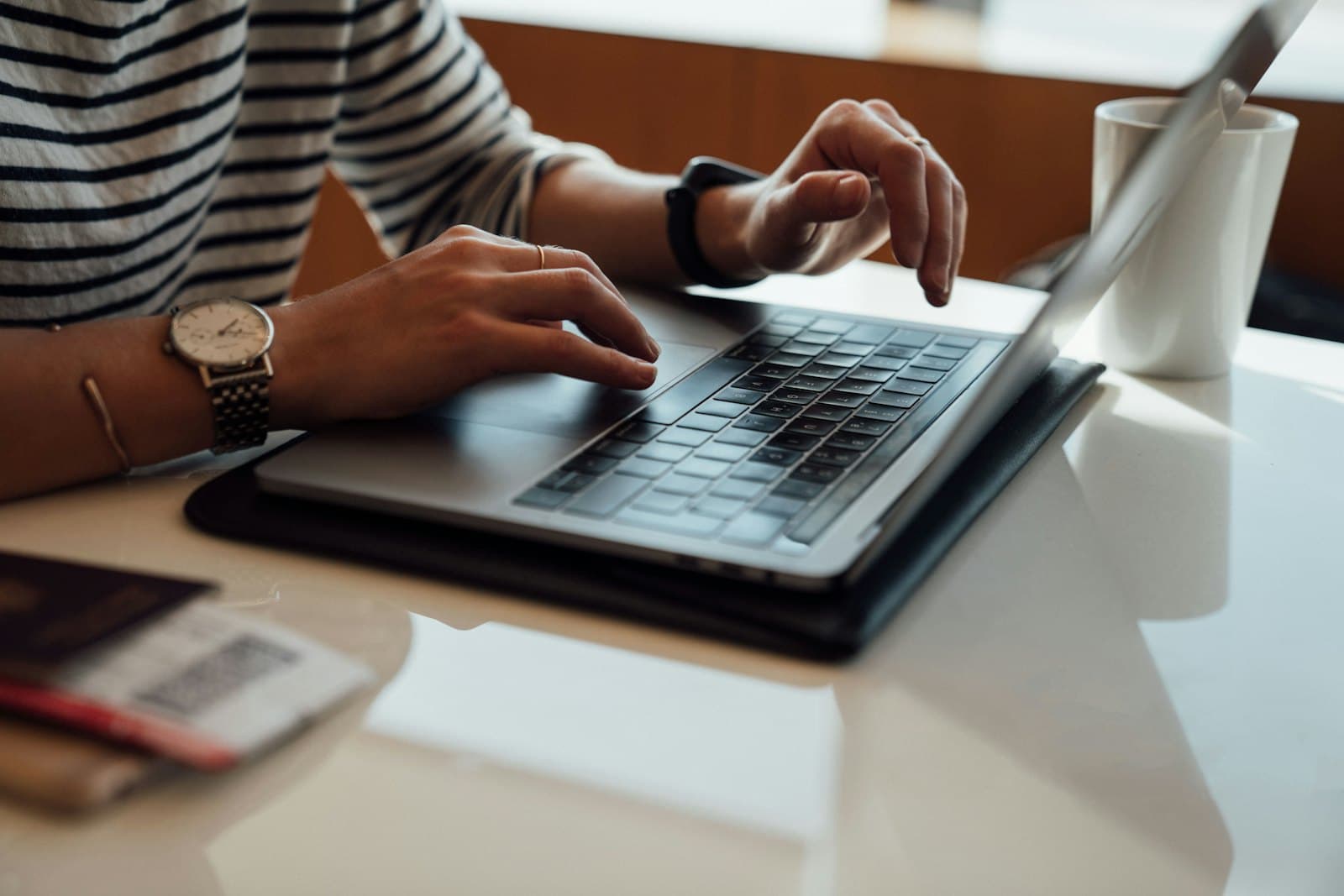 A person seated at a wooden table writing an email on a laptop