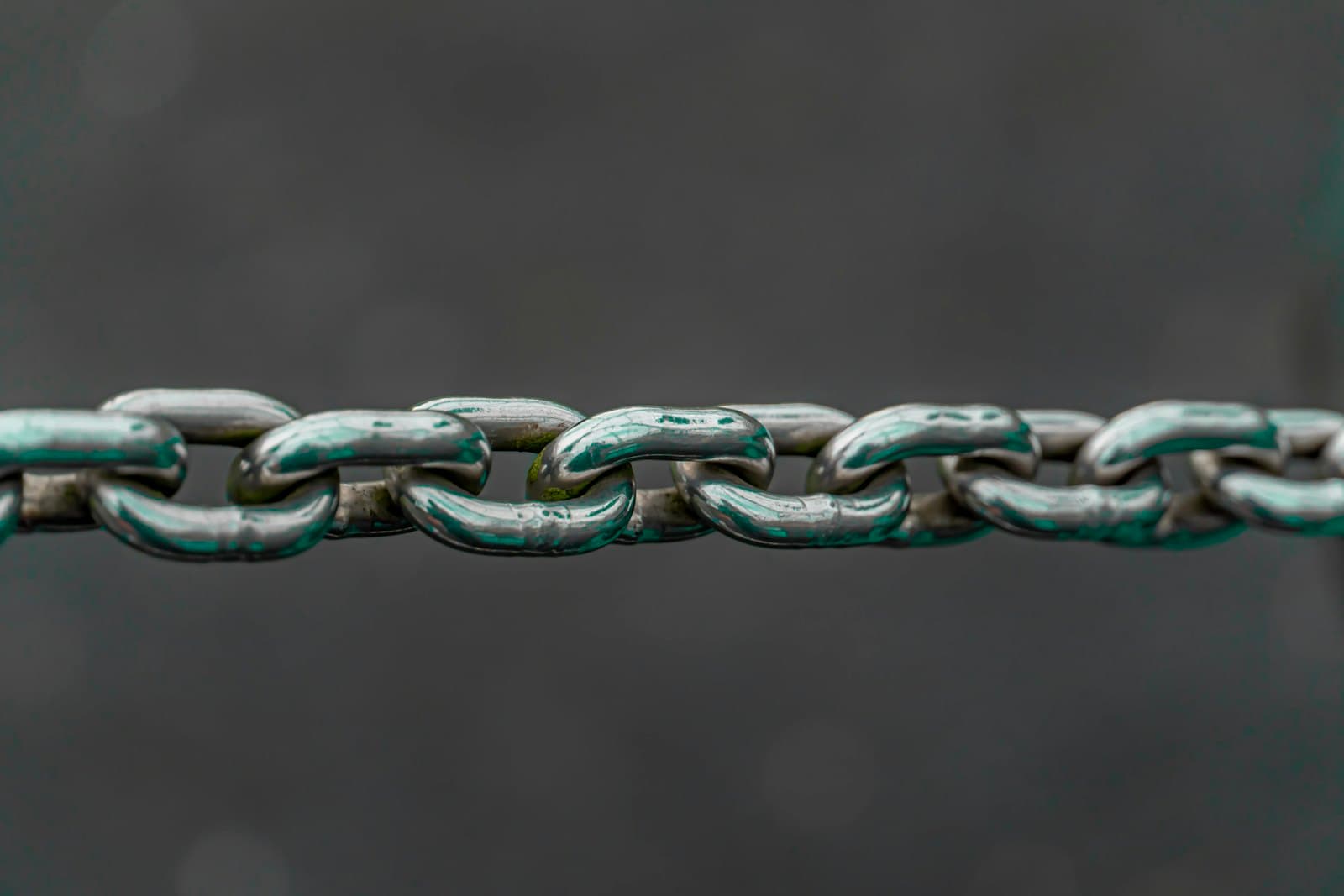A single metal chain stretched horizontally across a dark background